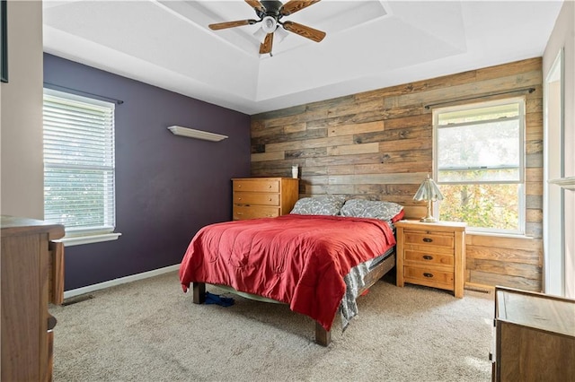 bedroom featuring wooden walls, light colored carpet, and ceiling fan