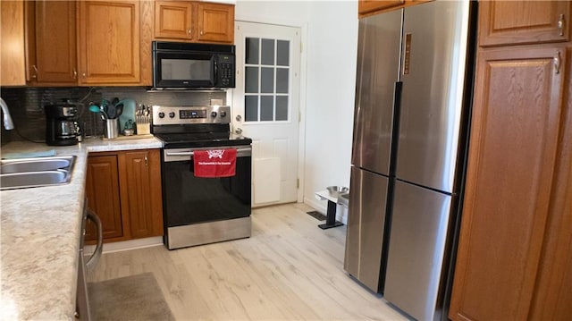 kitchen featuring decorative backsplash, stainless steel appliances, sink, and light hardwood / wood-style floors