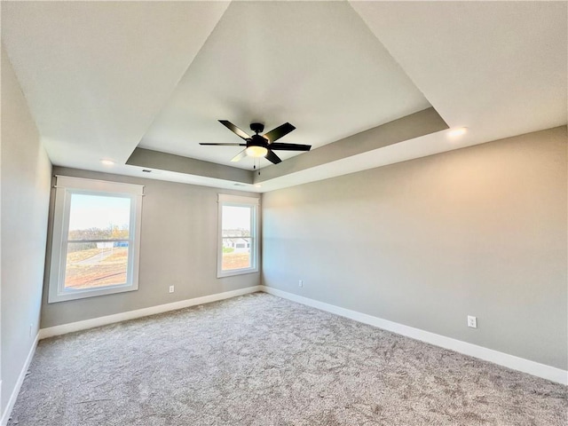 carpeted empty room featuring a raised ceiling and ceiling fan