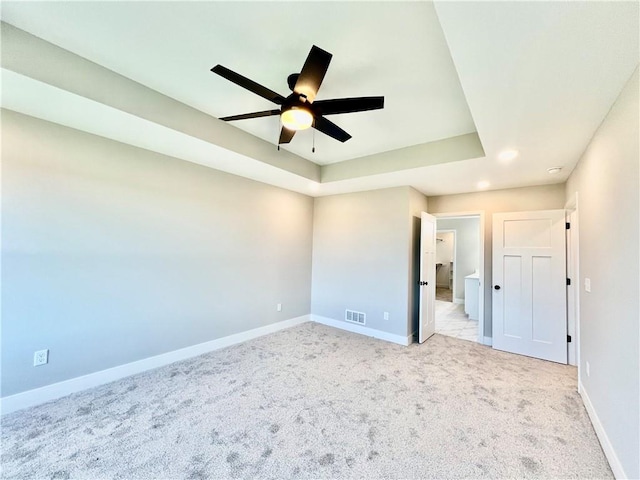 unfurnished bedroom with a tray ceiling, ceiling fan, and light colored carpet