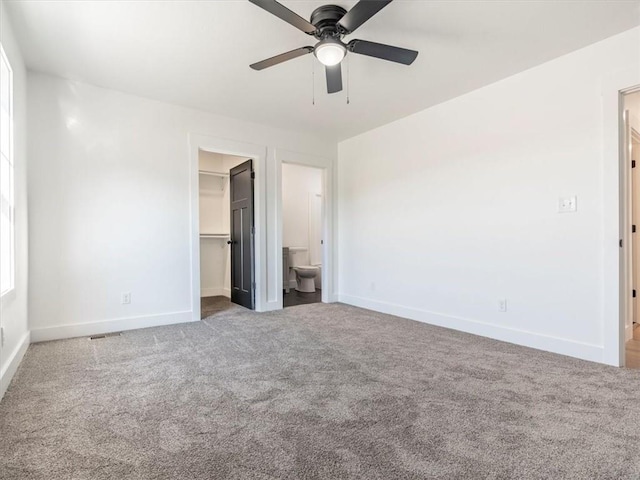 unfurnished bedroom featuring carpet flooring, ceiling fan, a spacious closet, connected bathroom, and a closet