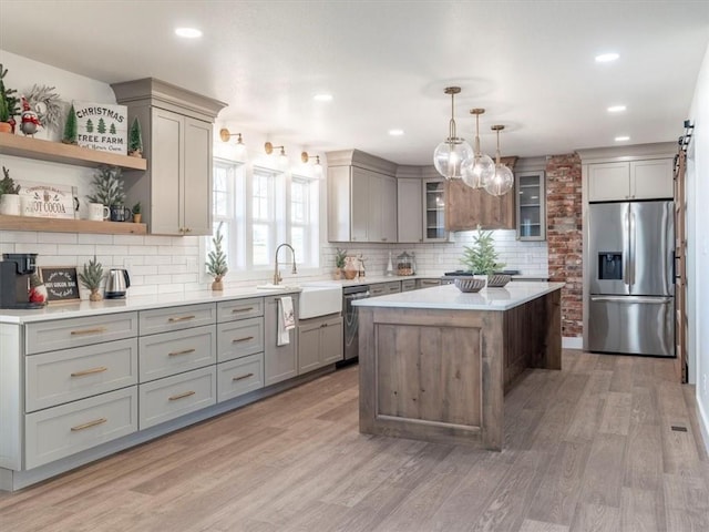 kitchen featuring a center island, backsplash, hardwood / wood-style floors, pendant lighting, and appliances with stainless steel finishes