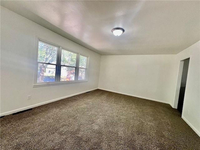 spare room featuring dark carpet