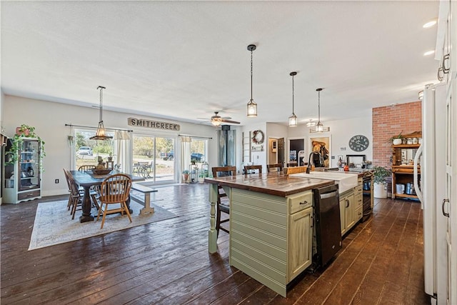 kitchen with ceiling fan, dishwasher, dark wood-type flooring, butcher block countertops, and a center island with sink