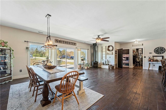 dining space featuring a wood stove, ceiling fan, and dark hardwood / wood-style floors