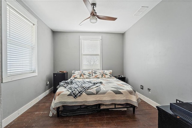 bedroom featuring ceiling fan, dark hardwood / wood-style flooring, and multiple windows