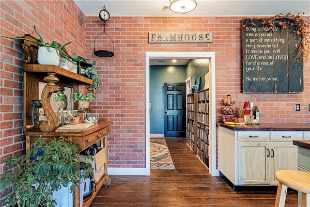 interior space with dark hardwood / wood-style floors and brick wall