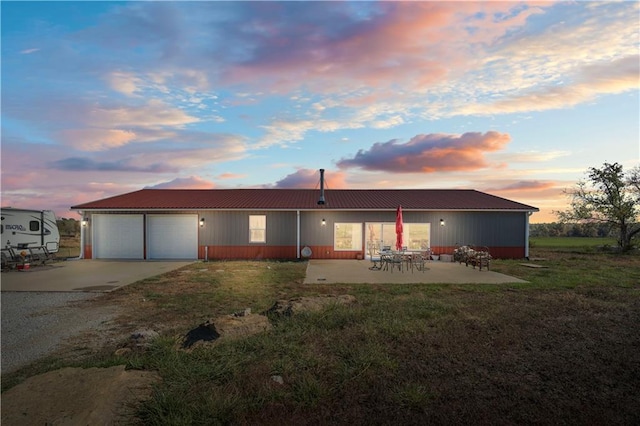 back house at dusk with a patio and a lawn