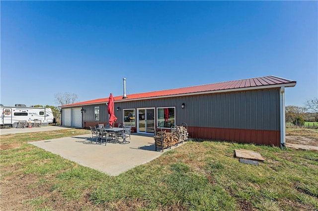 rear view of house featuring a lawn, a garage, and a patio