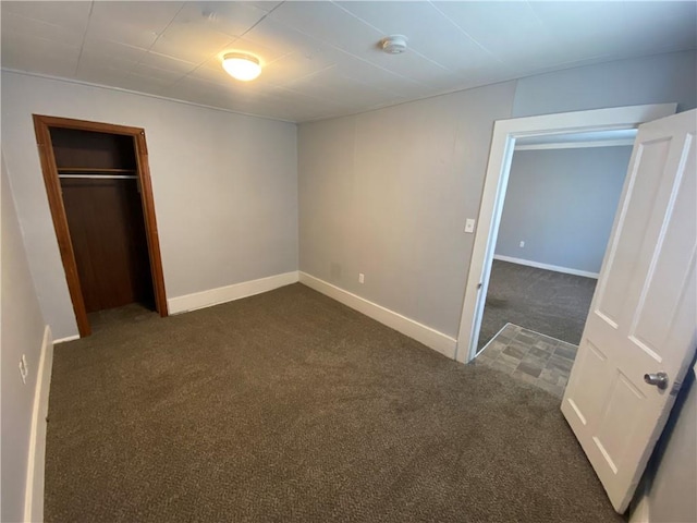 unfurnished bedroom with dark colored carpet and a closet