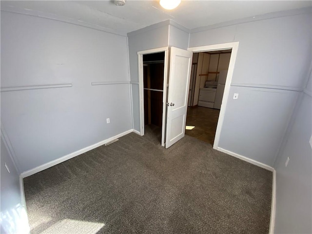 unfurnished bedroom featuring washer / dryer and dark carpet