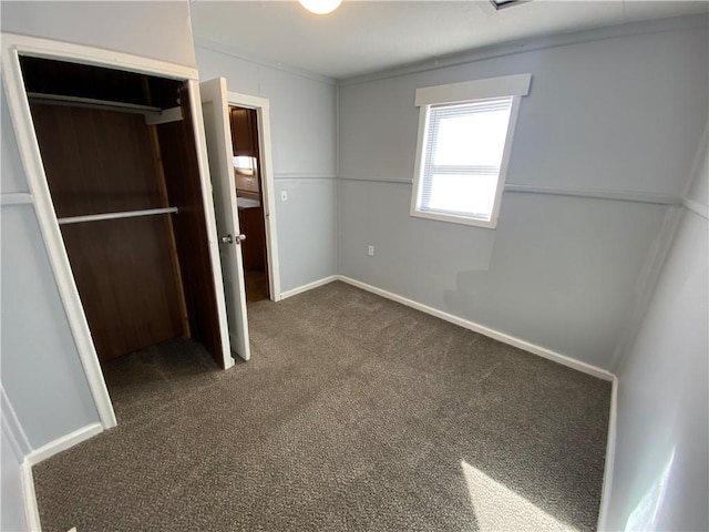 unfurnished bedroom with a closet and dark carpet