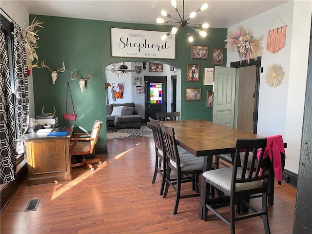 dining space featuring ceiling fan with notable chandelier and hardwood / wood-style flooring