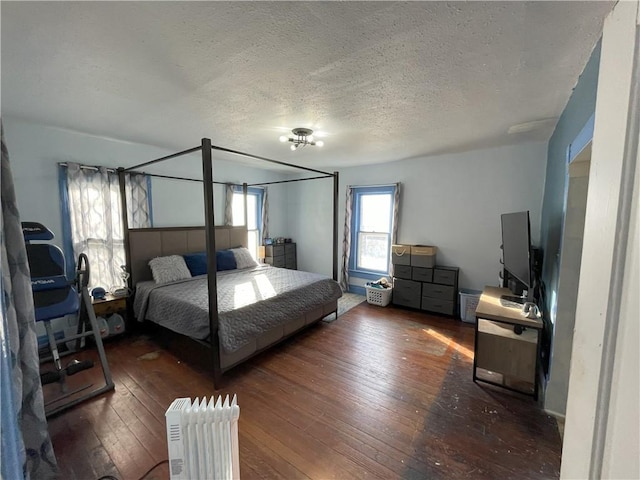 bedroom with dark hardwood / wood-style floors and a textured ceiling