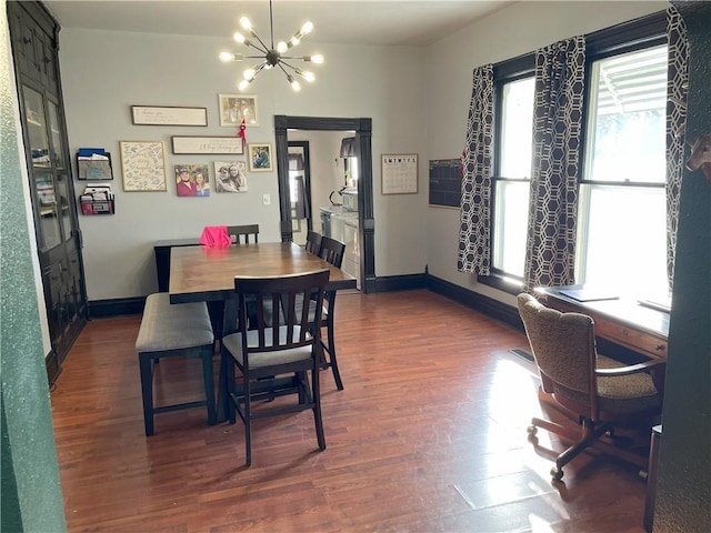 dining space featuring dark wood-type flooring and a notable chandelier