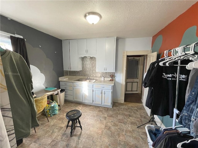513 W Ohio St, Butler, MO 64730 - kitchen featuring decorative backsplash, light countertops, stone finish floors, white cabinets, and a textured ceiling