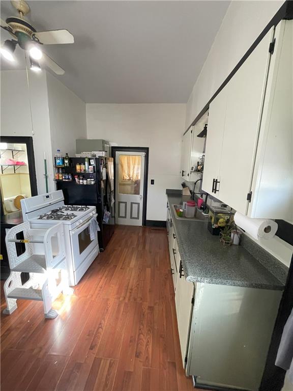 kitchen with ceiling fan, dark hardwood / wood-style flooring, white cabinets, and white appliances