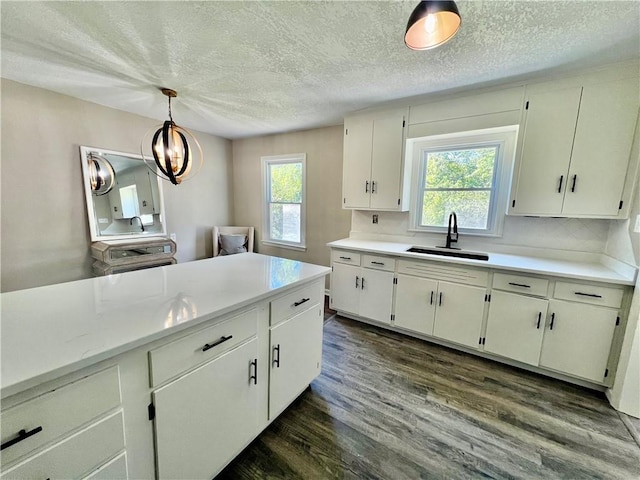 kitchen with a wealth of natural light, sink, hanging light fixtures, and dark wood-type flooring