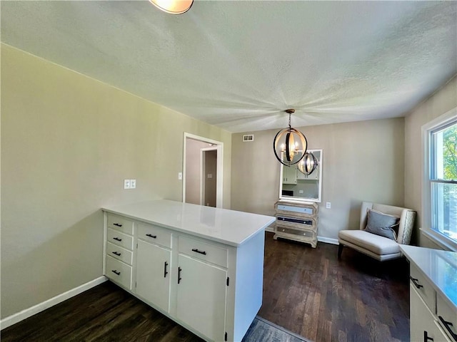 kitchen with kitchen peninsula, dark wood-type flooring, pendant lighting, a chandelier, and white cabinetry