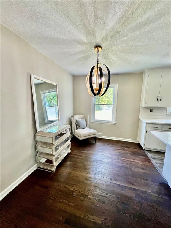 unfurnished room with a notable chandelier, dark hardwood / wood-style floors, and a textured ceiling