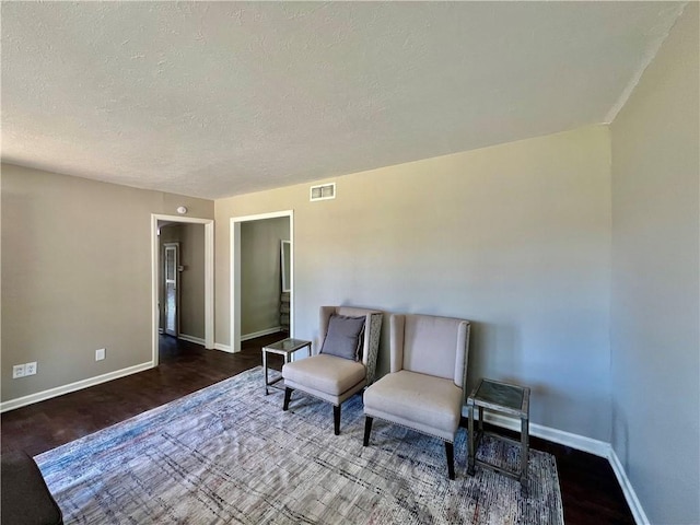 living area with wood-type flooring and a textured ceiling