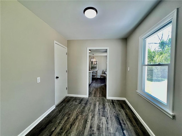 hallway with dark hardwood / wood-style flooring and a notable chandelier