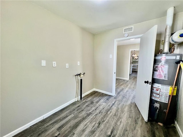 laundry area with dark hardwood / wood-style flooring and gas water heater