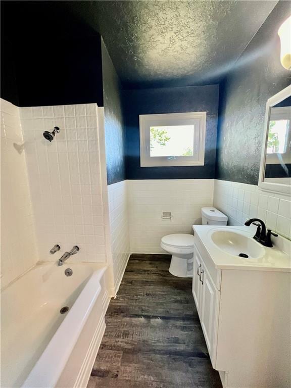 full bathroom featuring plenty of natural light, hardwood / wood-style floors, tile walls, and toilet