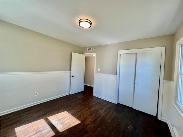 unfurnished bedroom with dark hardwood / wood-style flooring and a closet