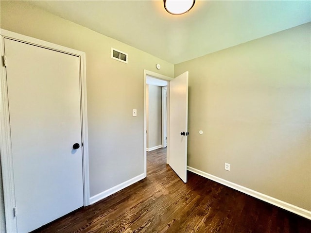 unfurnished bedroom featuring dark hardwood / wood-style floors and a closet