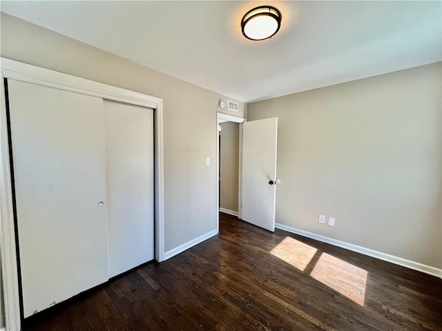 unfurnished bedroom with a closet and dark wood-type flooring