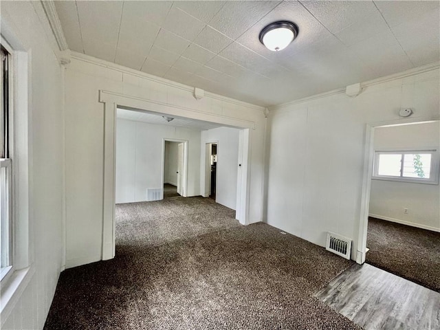 empty room featuring crown molding and carpet floors