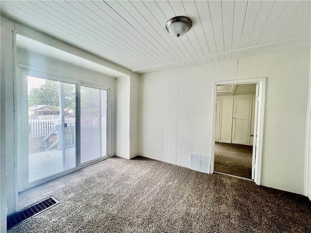 empty room featuring wood ceiling and carpet