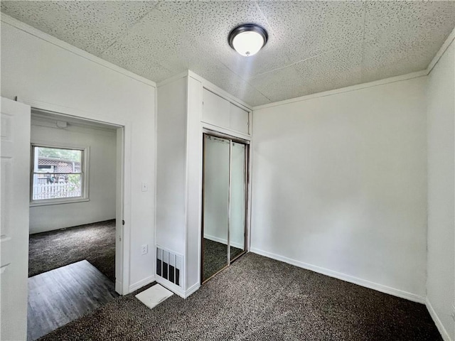 unfurnished bedroom featuring a closet and dark colored carpet