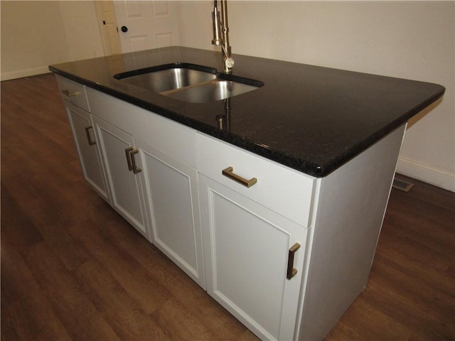 kitchen featuring sink, an island with sink, dark hardwood / wood-style floors, and white cabinets