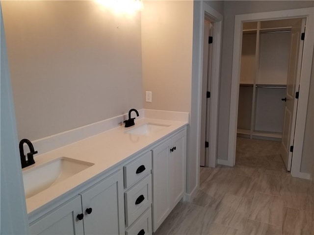 full bath featuring a sink, a spacious closet, and double vanity