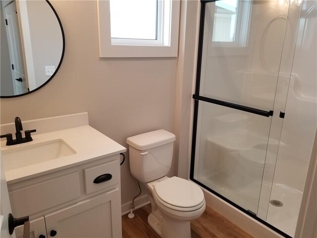 full bath with a stall shower, vanity, toilet, and wood finished floors