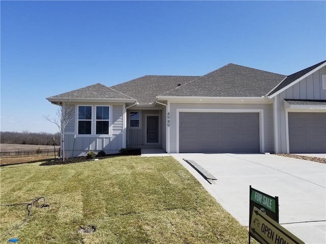 view of front facade featuring a garage, a shingled roof, concrete driveway, a front lawn, and board and batten siding