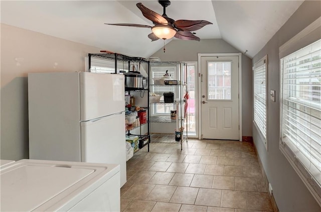 kitchen featuring washer / dryer, ceiling fan, vaulted ceiling, light tile patterned floors, and white refrigerator