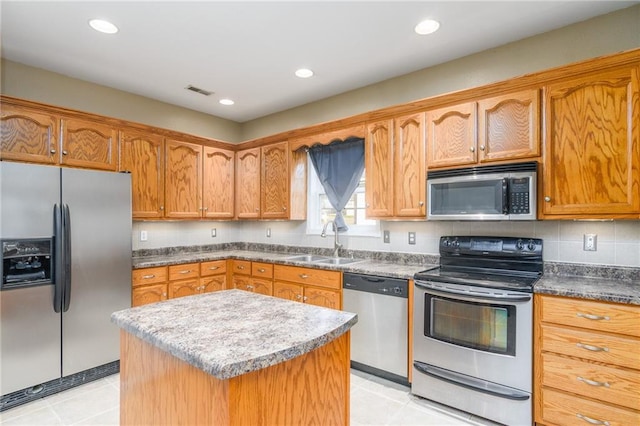 kitchen featuring sink, a center island, light tile patterned flooring, and appliances with stainless steel finishes