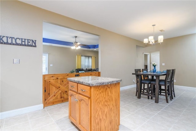 kitchen featuring light tile patterned floors, ceiling fan with notable chandelier, decorative light fixtures, and a kitchen island