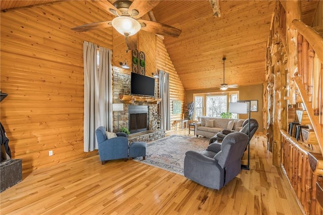 living room featuring wood walls, high vaulted ceiling, a fireplace, light hardwood / wood-style floors, and wood ceiling