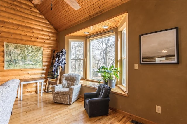 sitting room with rustic walls, lofted ceiling, and light wood-type flooring