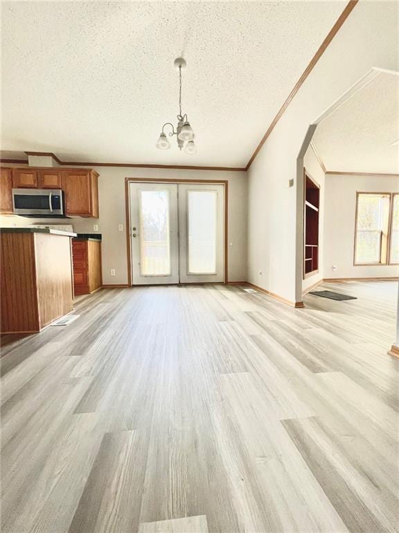 unfurnished living room featuring a chandelier, a textured ceiling, light hardwood / wood-style floors, and crown molding