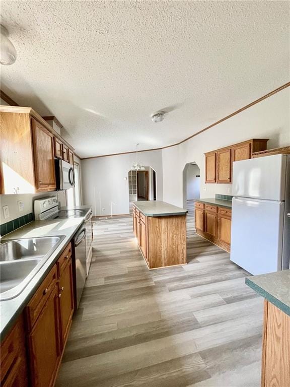 kitchen featuring a center island, sink, stainless steel appliances, light hardwood / wood-style floors, and pendant lighting