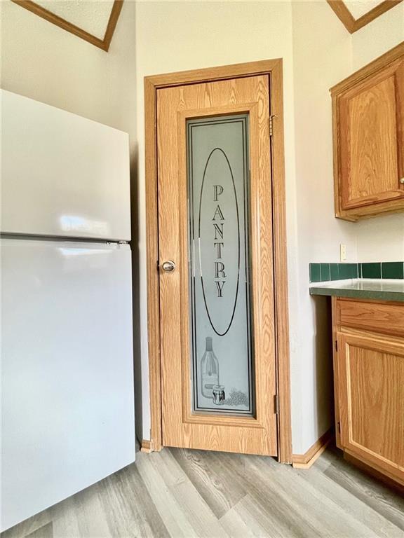 interior details with white refrigerator, light wood-type flooring, and crown molding