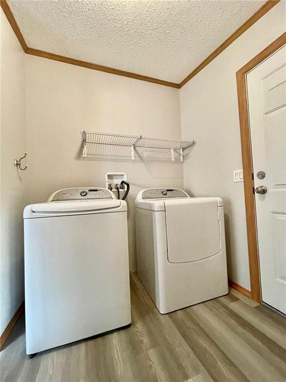 laundry room featuring hardwood / wood-style floors, washing machine and dryer, and crown molding