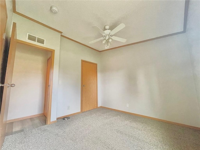 unfurnished room featuring a textured ceiling, ceiling fan, carpet floors, and crown molding