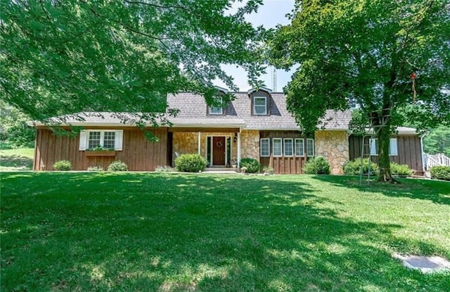 view of front of house with stone siding, roof with shingles, and a front lawn