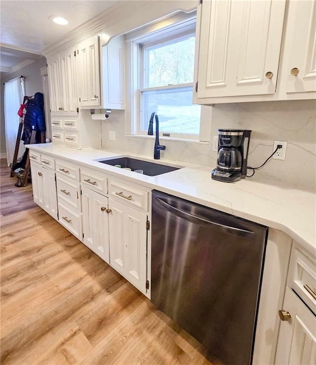 kitchen featuring light wood-style flooring, ornamental molding, a sink, stainless steel dishwasher, and white cabinetry